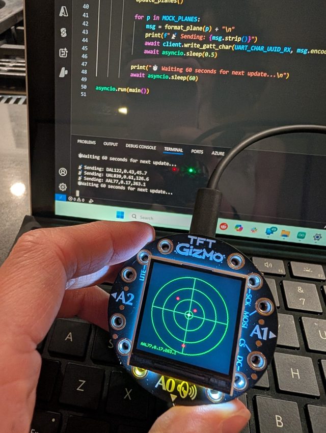Holding a TFT Gizmo display showing a live flight radar, built on the flight-tracker-bluefruit project